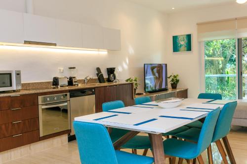 a kitchen with a dining table and blue chairs at Papaya 15 Apartments in Playa del Carmen