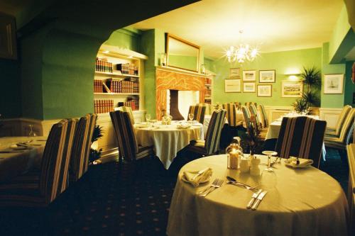 a restaurant with tables and chairs and a chandelier at Bishopsgate House Hotel in Beaumaris