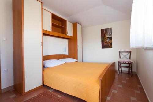 a small bedroom with a bed and a chair at Apartments Jadranka in Malinska