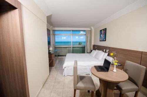 a hotel room with a bed and a table with a laptop at Hotel Jangadeiro in Recife