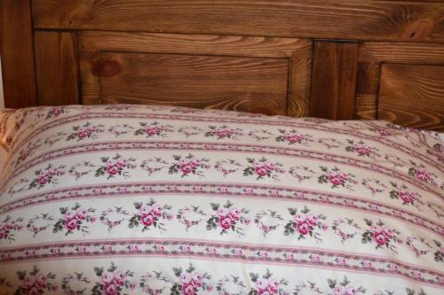 a bed with a pillow with pink flowers on it at Penzión Thamasy in Spišské Tomášovce