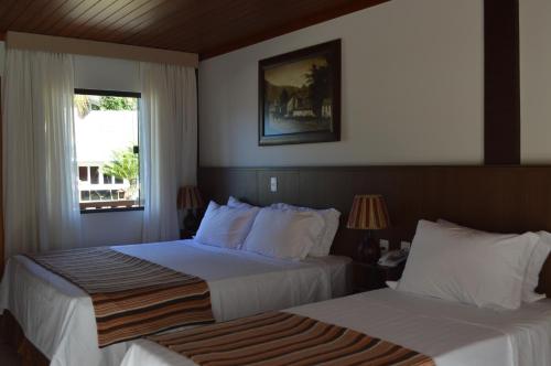 a hotel room with two beds and a window at Pousada Terê Parque in Teresópolis