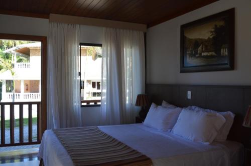 a bedroom with a bed and a large window at Pousada Terê Parque in Teresópolis