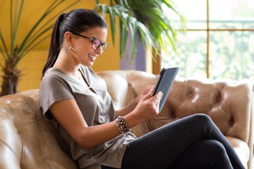 a woman sitting on a couch with a tablet at Hotel Santa Cruz Plaza in Santa Cruz