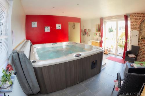 Cette chambre dispose d'un grand bain à remous et d'un mur rouge. dans l'établissement Bulles et Natures B&B, à Hergnies
