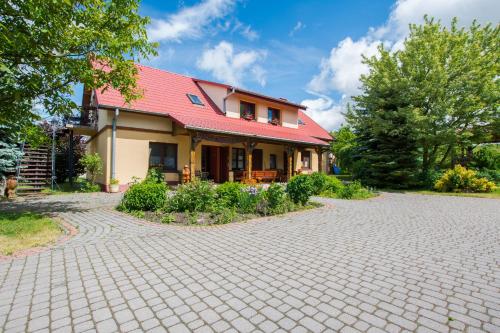 a house with a red roof and a brick driveway at Agroturystyka Pod Podkową in Mrągowo