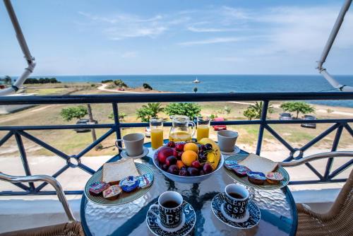 a table with a bowl of fruit and glasses of orange juice at Faros Apartments in Mytikas