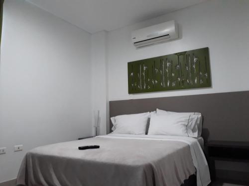 a bedroom with a bed with white sheets and a air conditioner at Hotel las Olas Malambo in Malambo