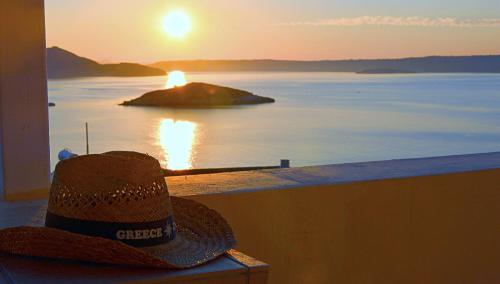 a hat sitting on a ledge watching the sunset at Manos Apartments in Almirida