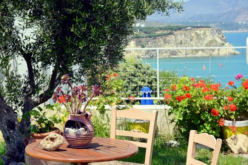 a table with a vase of flowers on a table with chairs at Manos Apartments in Almirida