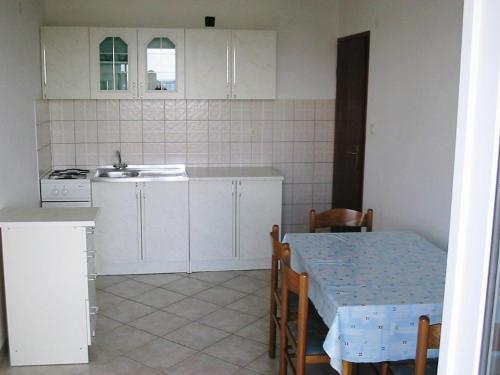 een keuken met witte kasten, een tafel en een wastafel bij Apartments Selez in Mandre
