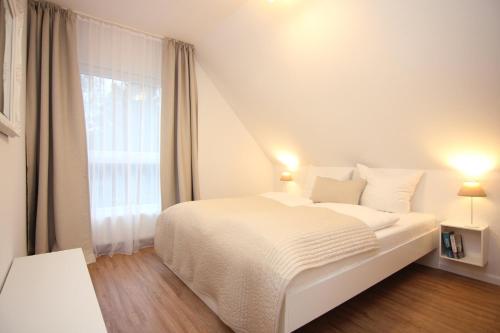 ein weißes Schlafzimmer mit einem Bett und einem Fenster in der Unterkunft Ferienwohnung Koje 44 in Timmendorfer Strand
