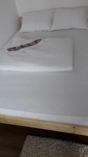 a white bed with a book on top of it at Lörincz Vendégház in Corund