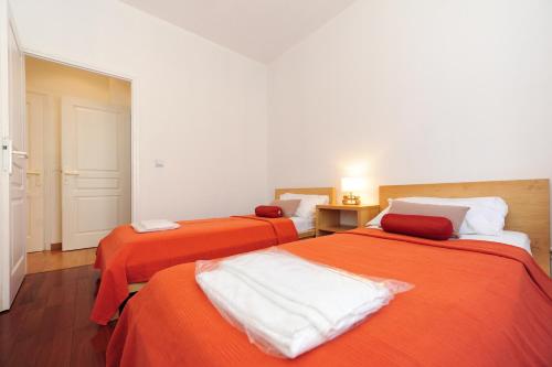 2 Betten in einem Zimmer mit orangefarbener Bettwäsche in der Unterkunft Appartamento La Terrasse Zen Five stars Holiday House in Nizza