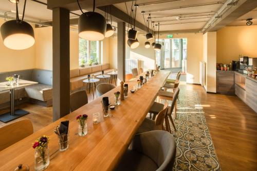 a long table in a restaurant with chairs and tables at Pura Vida Hotel Cuxhaven in Cuxhaven