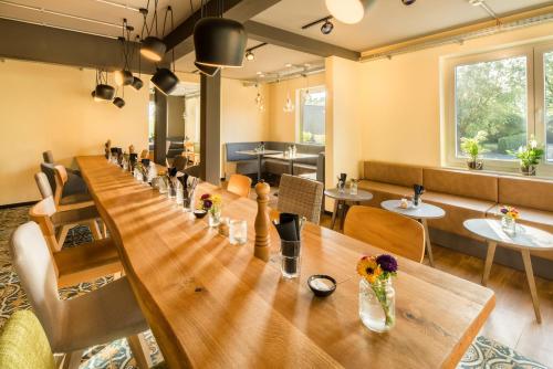 a long table in a restaurant with flowers on it at Pura Vida Hotel Cuxhaven in Cuxhaven