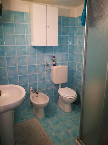 a blue tiled bathroom with a toilet and a sink at Villa Caterina in Mondello