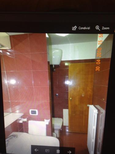 baño con aseo y pared de azulejos rojos en Casa vacanze "Le tre sorelle", en San Benedetto del Tronto