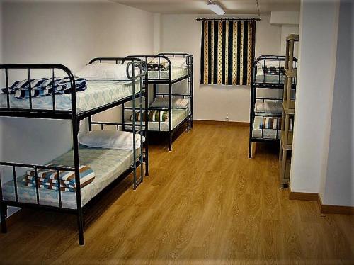 a room with three bunk beds and a wooden floor at Albergue Irugoienea in Espinal-Auzperri
