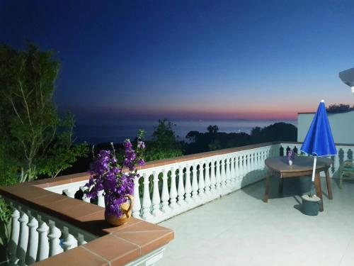 a balcony with a table and a blue umbrella at Mazzitelli Apartment in Capo Vaticano