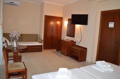 a hotel room with a bed and a table and a television at Hotel Strimoniko in Asprovalta