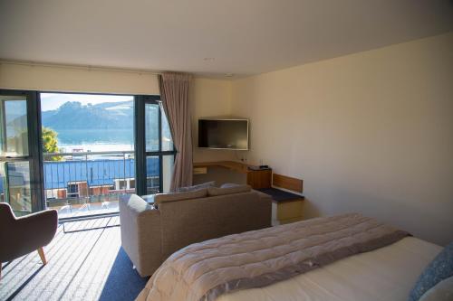 a bedroom with a bed and a couch and a television at Akaroa Criterion Motel in Akaroa