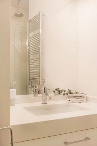 une salle de bain blanche avec un lavabo et un miroir dans l'établissement Two Bedroom Luxury Apartment - Balcony with View of Notre Dame, à Paris