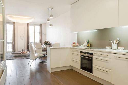 une cuisine avec des placards blancs et une salle à manger dans l'établissement Two Bedroom Luxury Apartment - Balcony with View of Notre Dame, à Paris