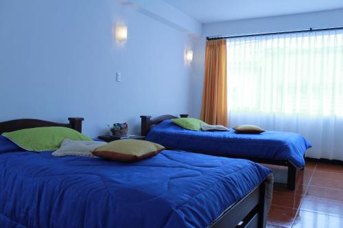 a bedroom with two beds with blue sheets and a window at Hotel Royal Suite in Manizales