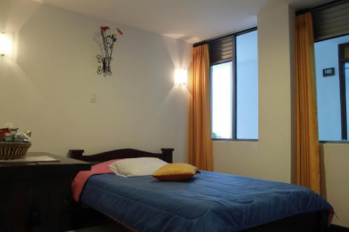 a bedroom with a bed and a desk and a window at Hotel Royal Suite in Manizales