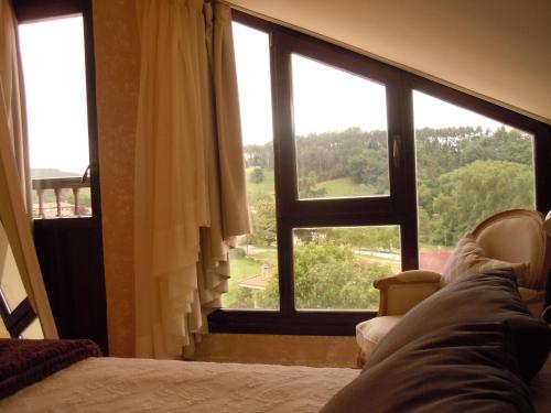 a bedroom with a large window with a view at Posada La Torre de los Isla & Spa in Beranga