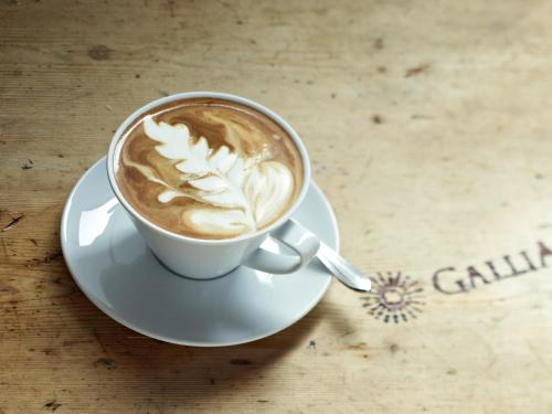 a cup of coffee on a plate on a table at Hotel Gallia in Stelvio