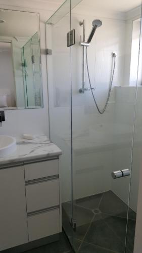 a bathroom with a glass shower with a sink at Banyandah Towers in Maroochydore