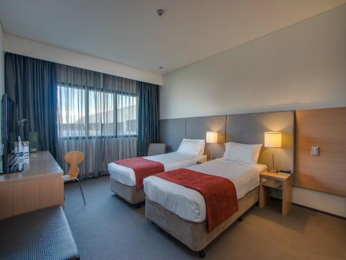 a hotel room with two beds and a television at Alpha Hotel Eastern Creek in Blacktown