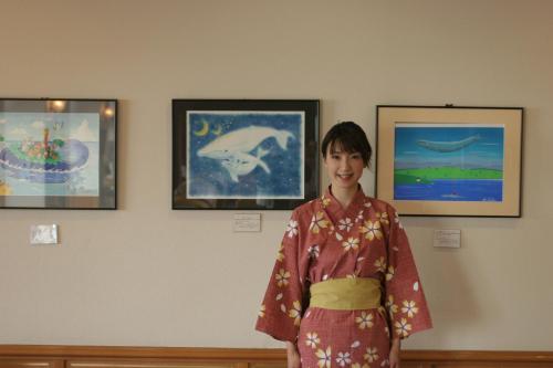 a woman in a kimono standing in front of paintings at Tabinoyado Ushionoakari Geiboso in Shima