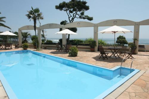 a large swimming pool with tables and umbrellas at Tabinoyado Ushionoakari Geiboso in Shima
