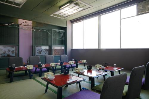 a dining room with tables and chairs and large windows at Tabinoyado Ushionoakari Geiboso in Shima