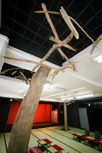 a room with red chairs and a tree branch hanging from the ceiling at Tabinoyado Ushionoakari Geiboso in Shima