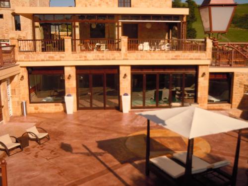 a patio with chairs and an umbrella in front of a building at Posada La Torre de los Isla & Spa in Beranga