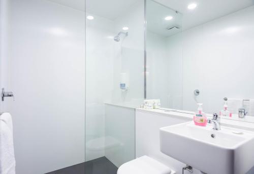 a white bathroom with a sink and a shower at Buller Central Hotel in Mount Buller