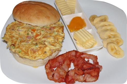 a plate of food with an omelet and a sandwich and other foods at Deep Forest Garden Hotel in Puerto Princesa City