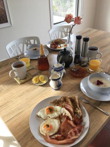 a wooden table with plates of breakfast food on it at Rosewhite House in Myrtleford