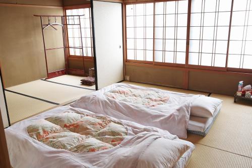 a room with two beds in a room with windows at Komachiya in Kyoto