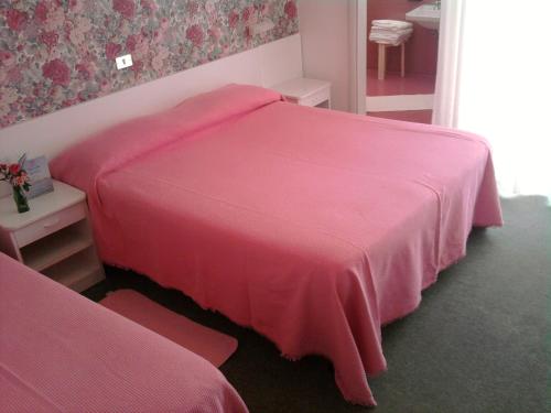 a bedroom with a pink bed and a table at Hotel Gioiella Depandance in Bellaria-Igea Marina