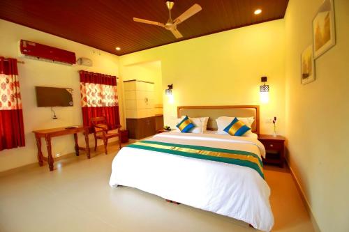1 dormitorio con 1 cama blanca grande y escritorio en Casa Marari, en Mararikulam