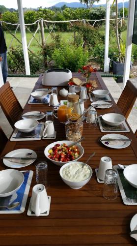 a wooden table topped with plates and bowls of food at Jacaranda Lodge in Coromandel Town