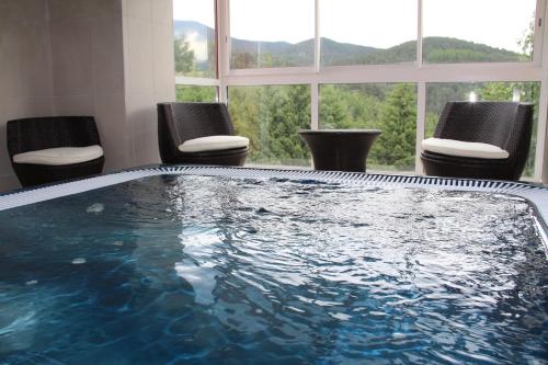 ein großer Pool in einem Zimmer mit Stühlen in der Unterkunft Hotel Corrieu in La Llagonne