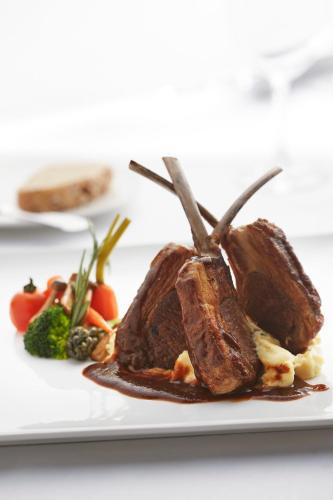 a piece of food on a plate with vegetables at THE FACE Suites Hotel in Kuala Lumpur