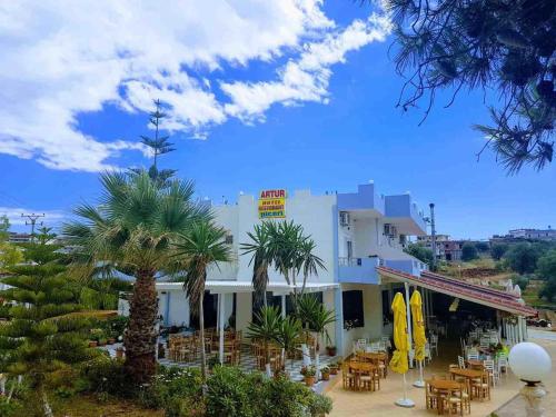 a hotel with tables and chairs and palm trees at Hotel Artur in Ksamil