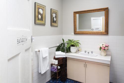 ein Bad mit einem Waschbecken und einem Spiegel in der Unterkunft Southern Railway Hotel Goulburn in Goulburn